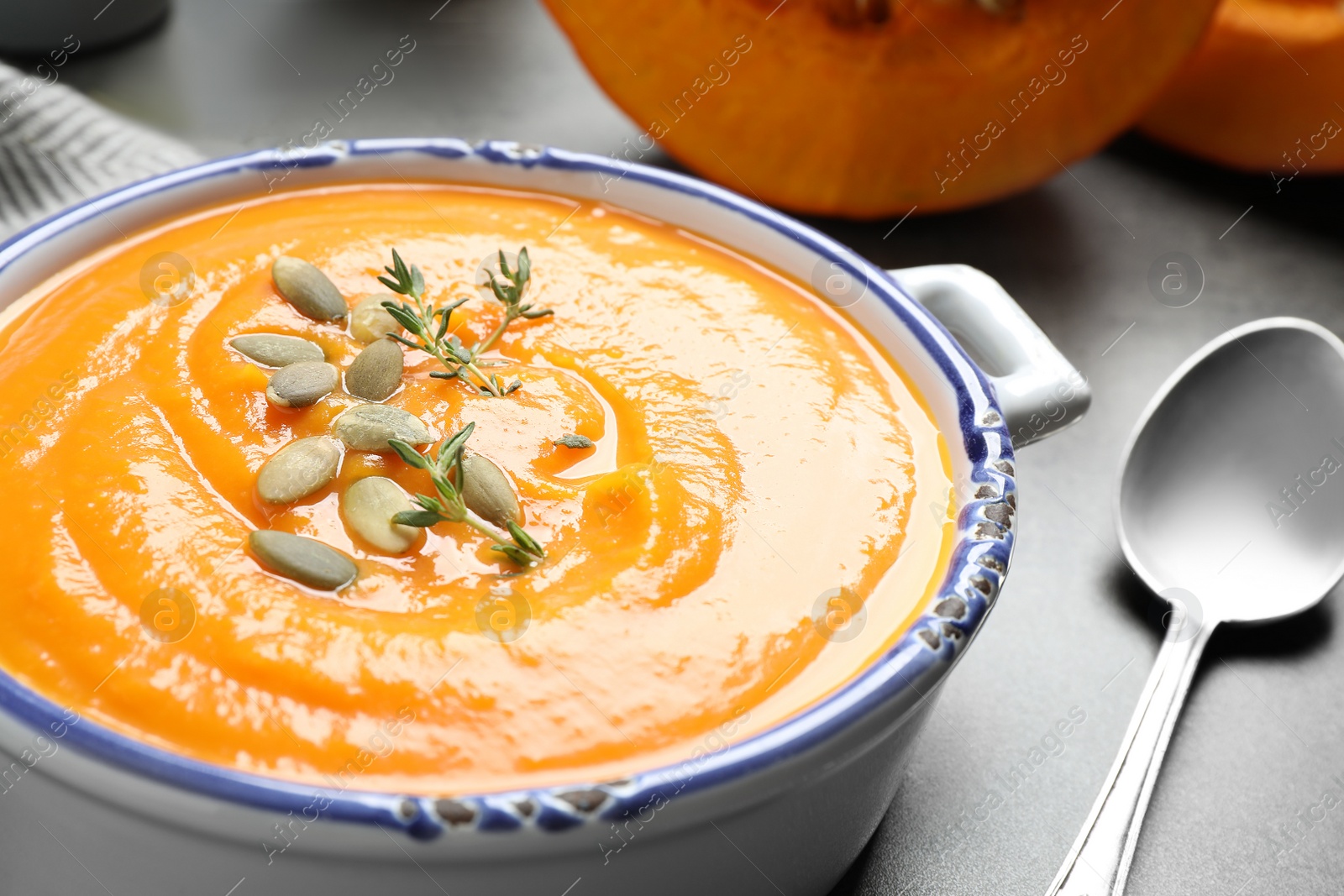 Photo of Delicious pumpkin soup in bowl on grey table, closeup