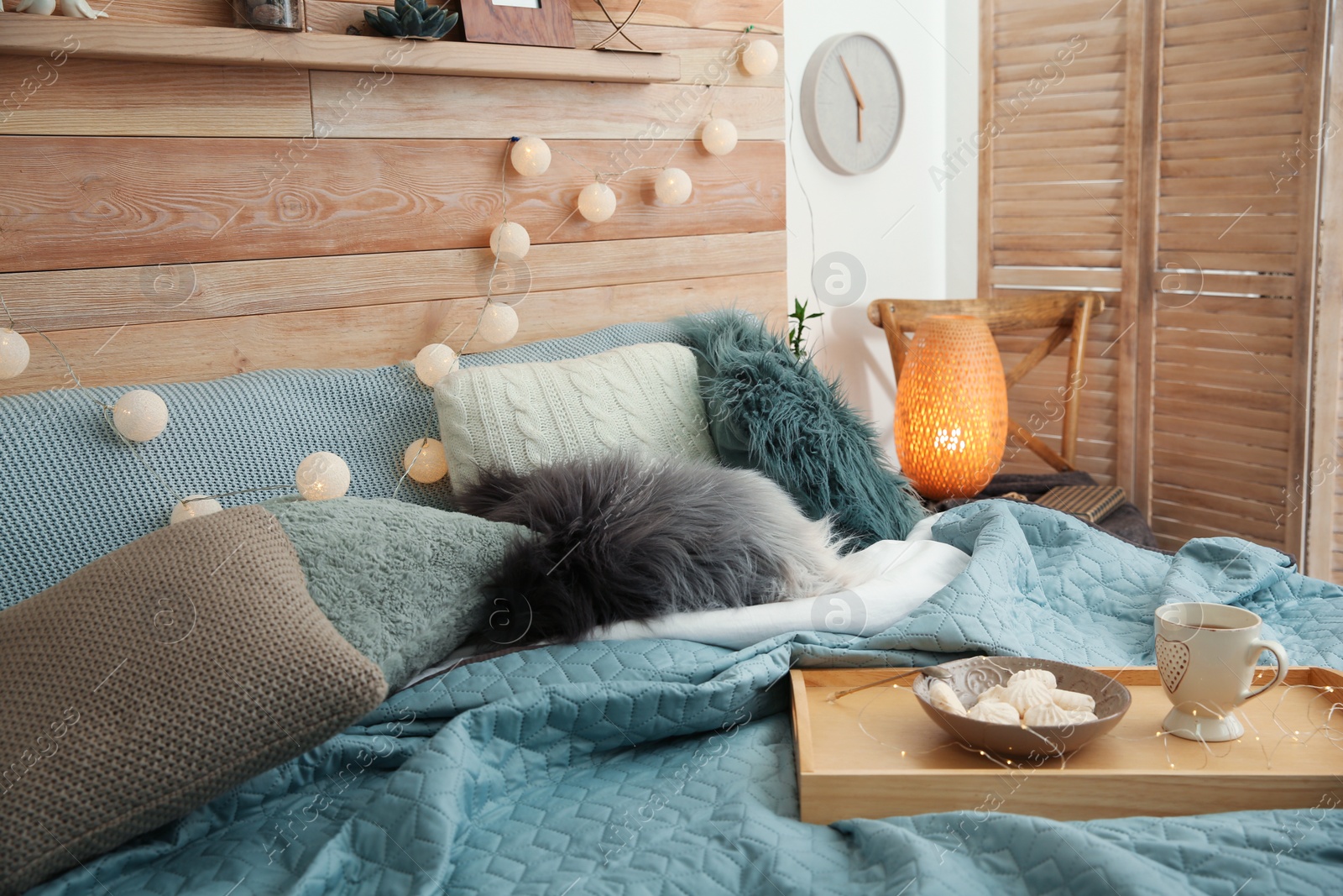 Photo of Different pillows and tray with breakfast on bed in room. Idea for interior decor