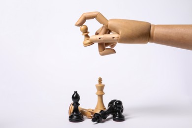 Photo of Robot holding pawn over other chess pieces on white background. Wooden hand representing artificial intelligence