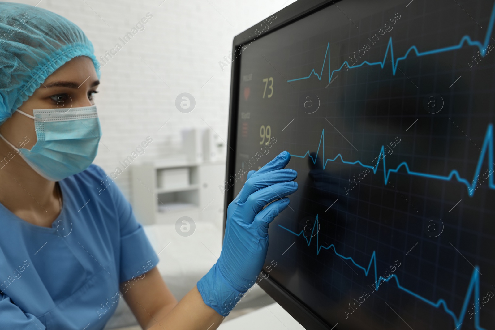 Photo of Nurse near monitor with cardiogram in hospital, closeup