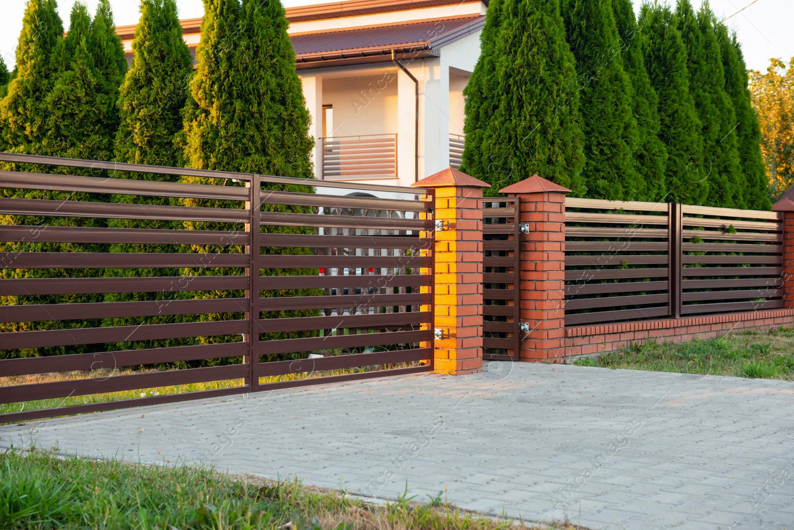 Photo of Beautiful brick fence with iron panels outdoors