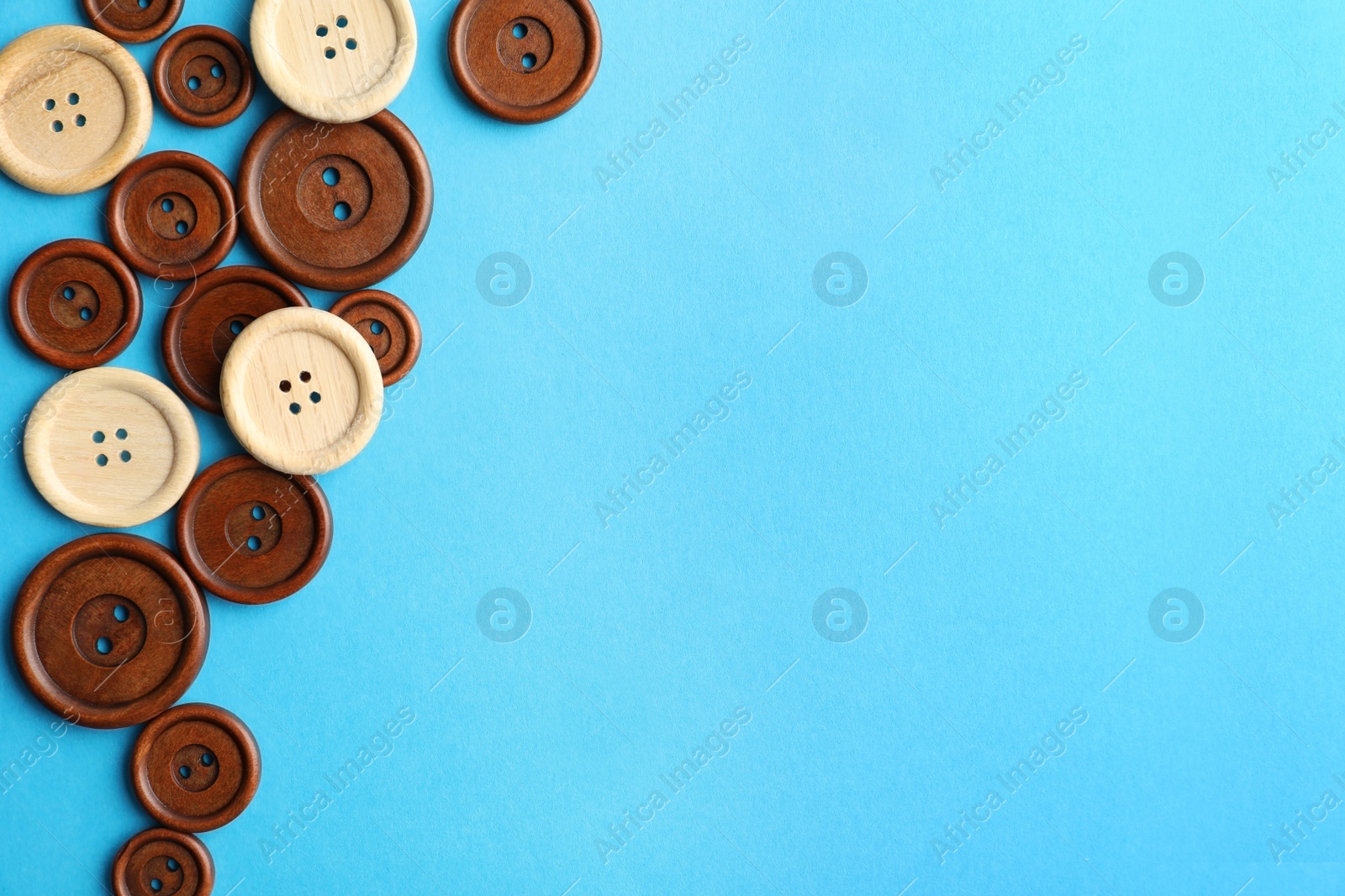 Photo of Many colorful sewing buttons on light blue background, flat lay. Space for text