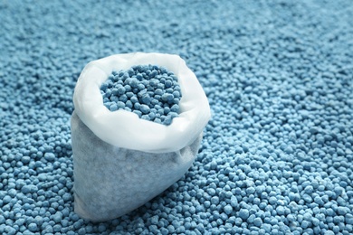 Bag and granular mineral fertilizer, closeup with space for text