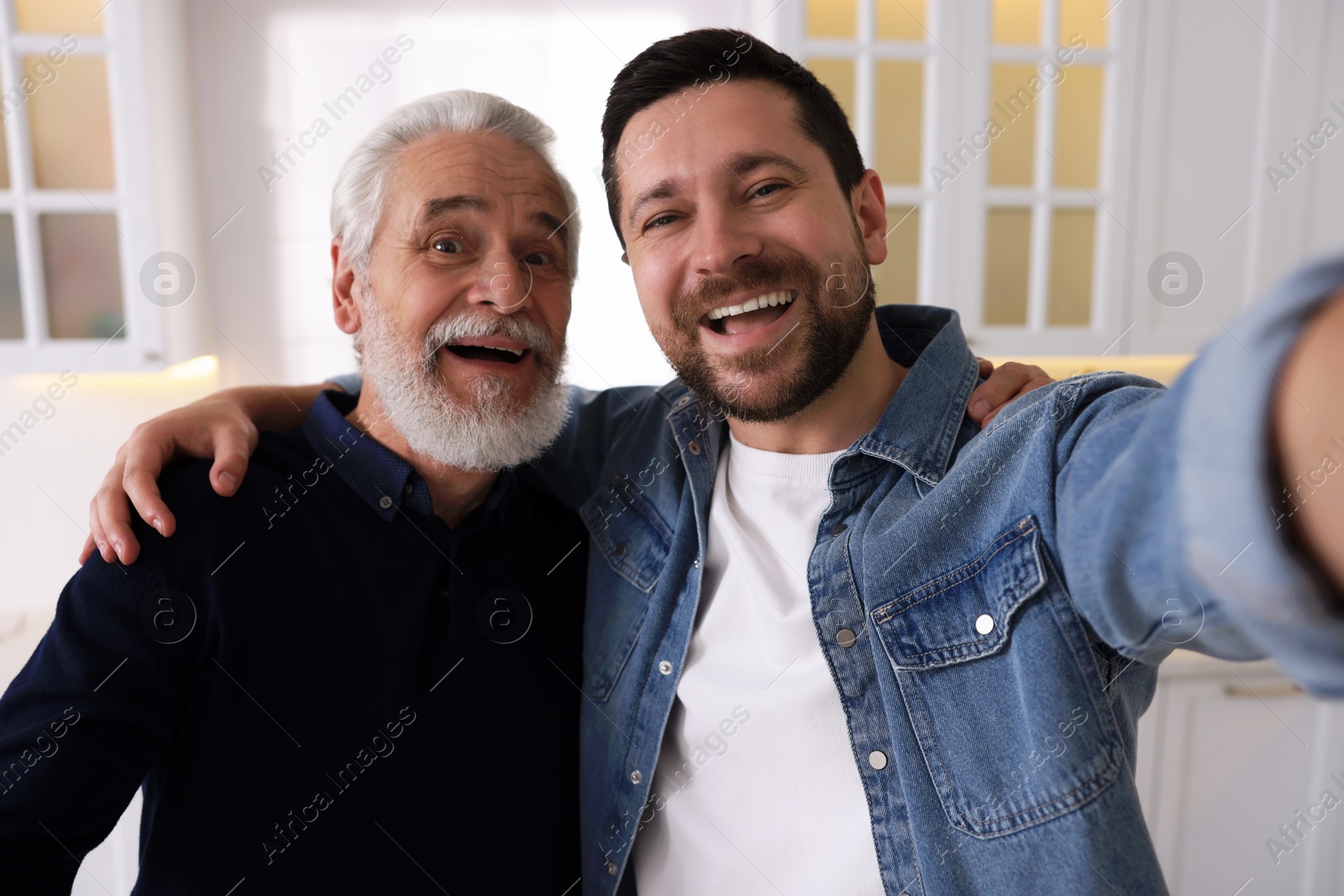 Photo of Happy son and his dad taking selfie at home