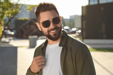 Photo of Handsome smiling man in sunglasses on city street