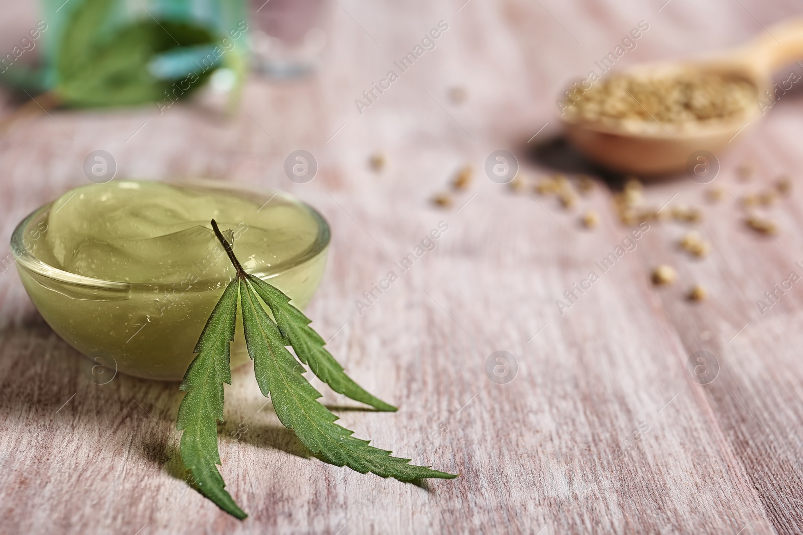 Photo of Bowl with hemp lotion on wooden table