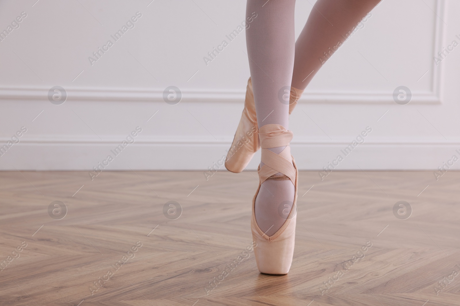 Photo of Little ballerina practicing dance moves in studio, closeup of legs. Space for text