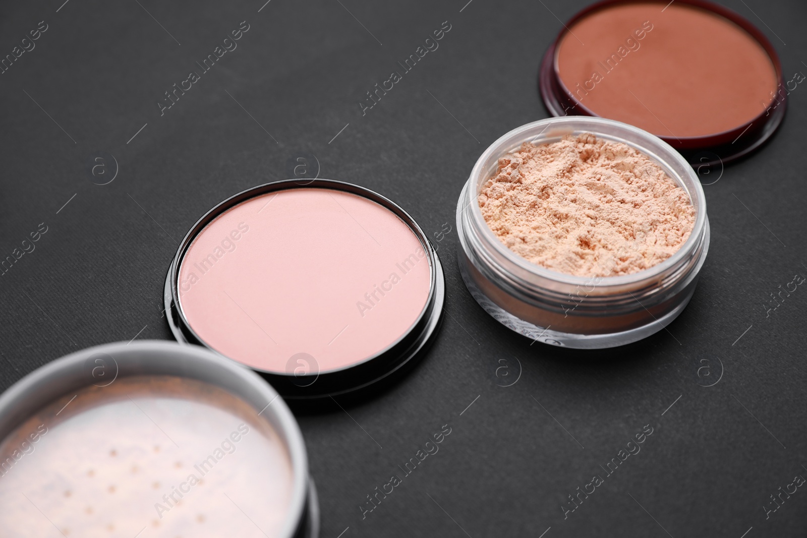 Photo of Different face powders on black background, closeup