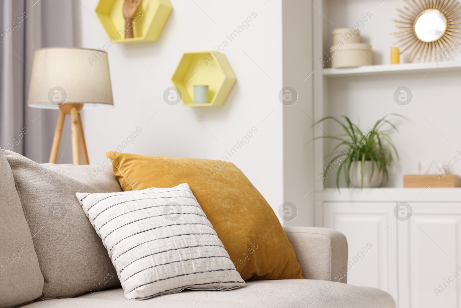 Photo of Spring atmosphere. Soft sofa, lamp and shelves with stylish accessories in room