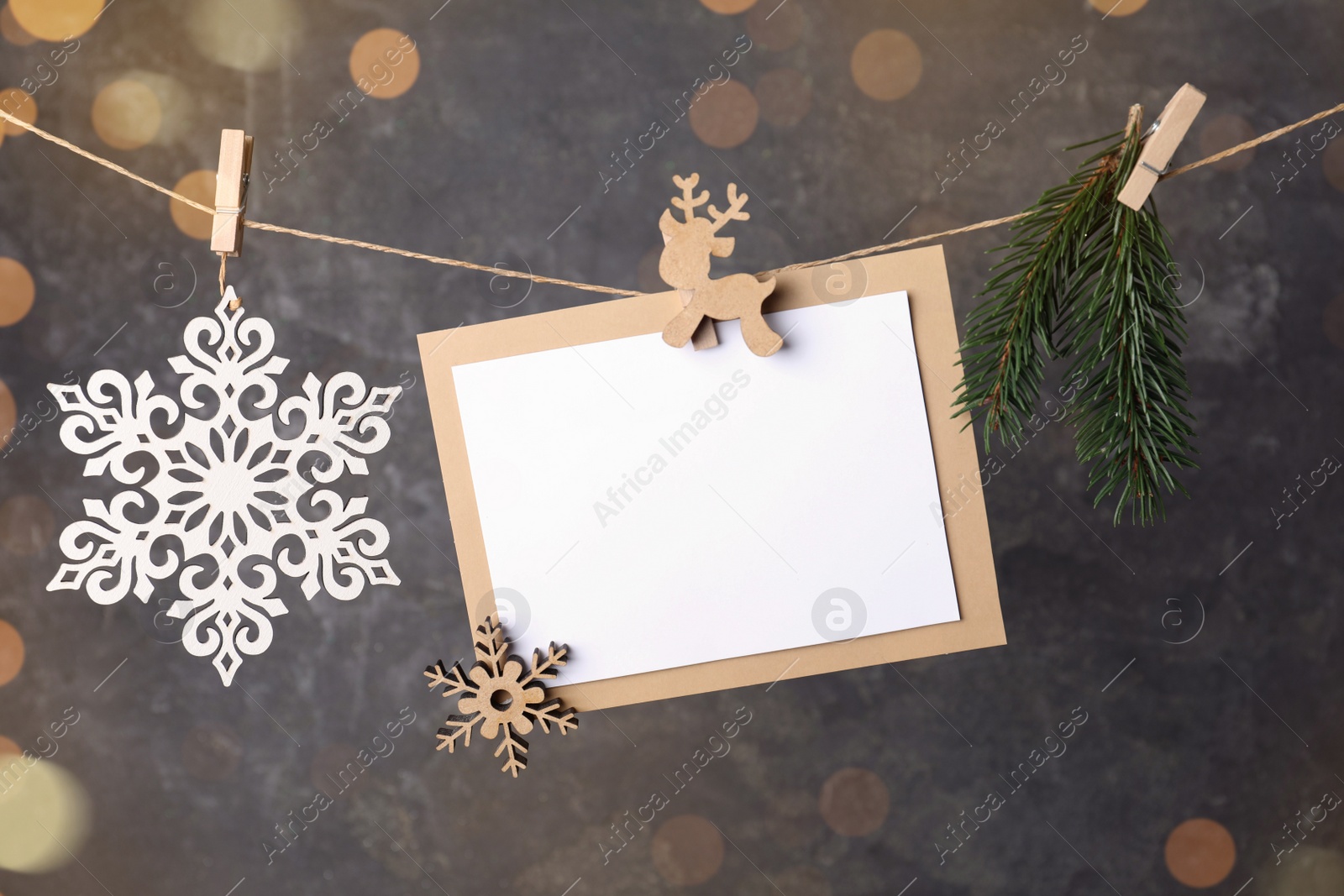 Photo of Blank Christmas card and festive decor on rope against grey background, space for text