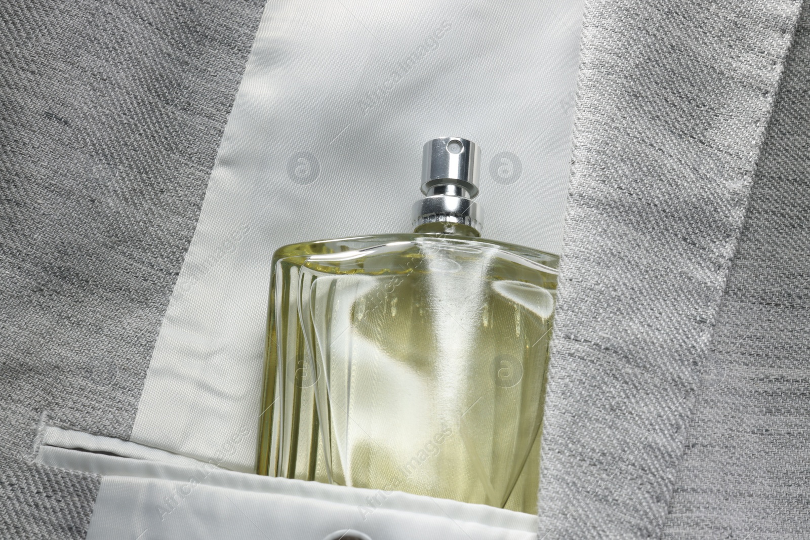 Photo of Luxury men's perfume in inner pocket of grey jacket, top view