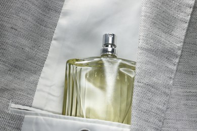 Luxury men's perfume in inner pocket of grey jacket, top view