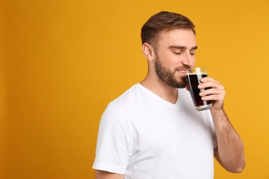 Photo of Handsome man with cold kvass on yellow background. Traditional Russian summer drink