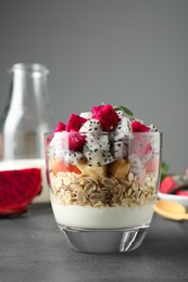 Photo of Glass of granola with different pitahayas, yogurt and other fruits on grey table