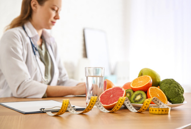Photo of Healthy products, measuring tape and blurred nutritionist on background