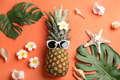 Photo of Flat lay composition with pineapple, sunglasses and beach items on orange background. Creative concept