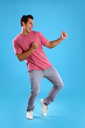 Photo of Handsome young man dancing on blue background