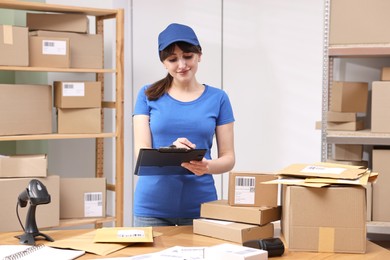 Parcel packing. Post office worker with clipboard at wooden table indoors