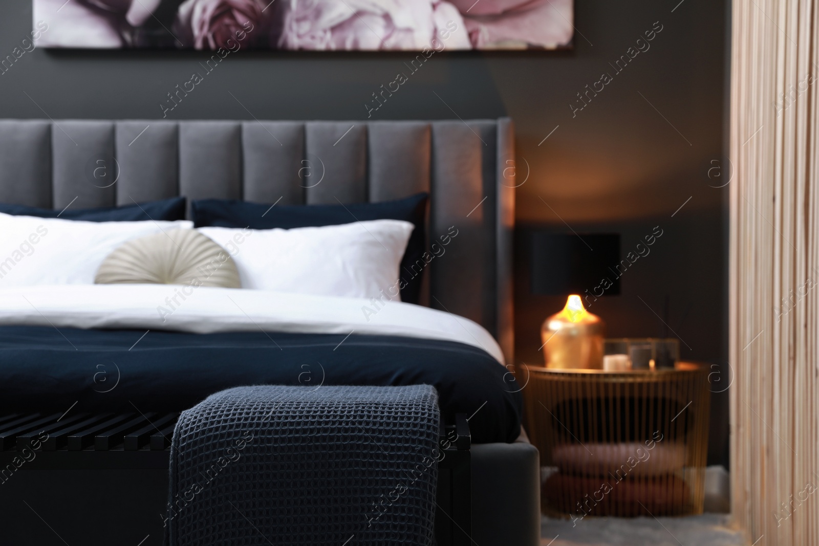 Photo of Comfortable bed with cushions and ottoman in room. Stylish interior