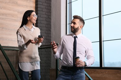 Photo of Coworkers talking during coffee break on stairs in office