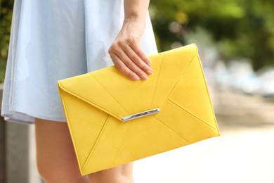 Photo of Young woman with elegant envelope bag outdoors on summer day, closeup