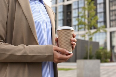 Coffee to go. Woman with paper cup of drink outdoors, closeup