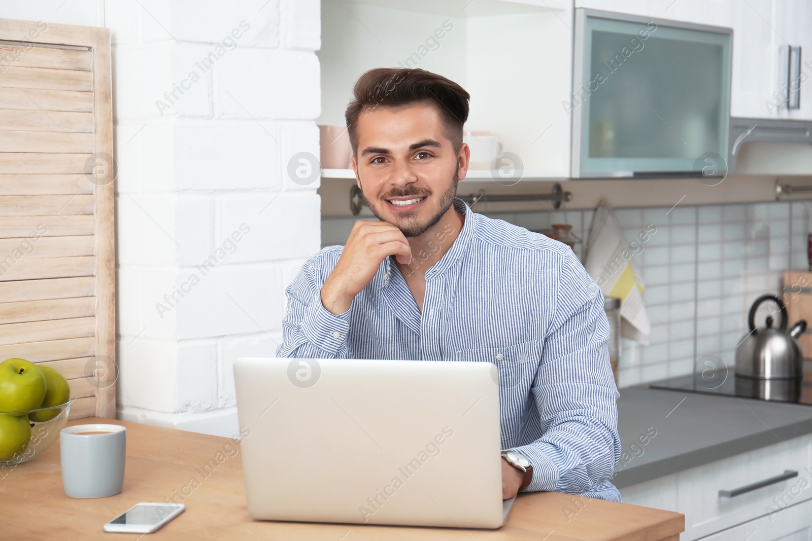 Photo of Man in casual clothes using laptop at table indoors
