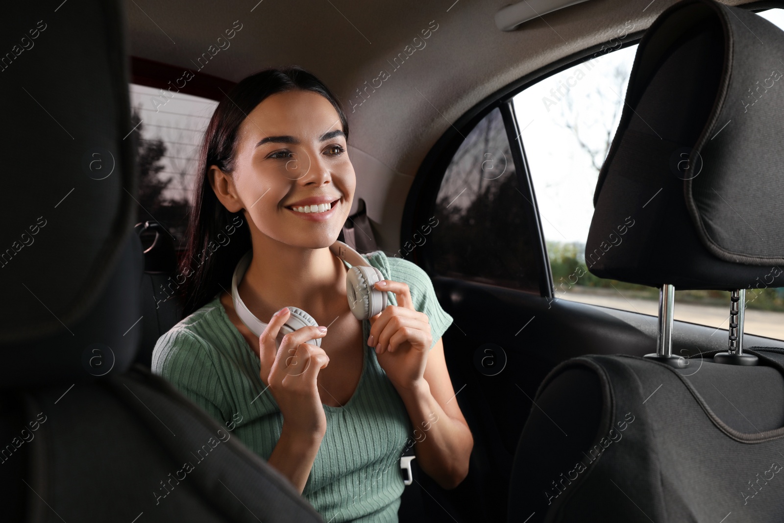 Photo of Young woman with headphones in modern taxi