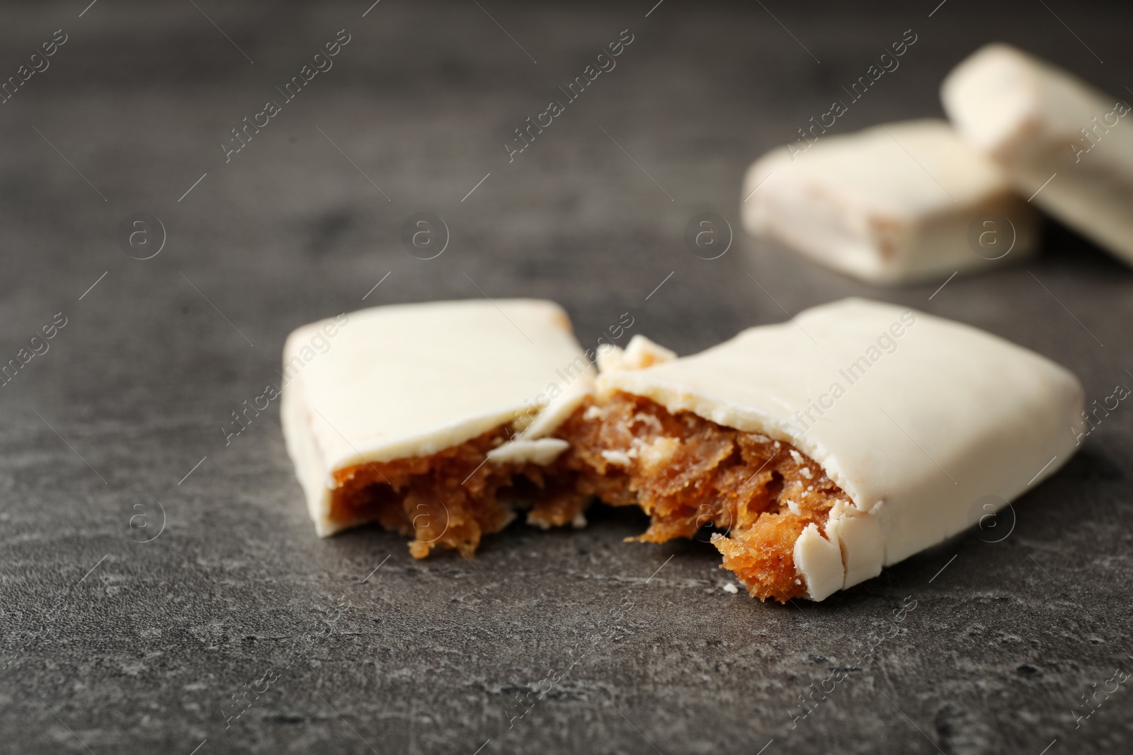 Photo of Pieces of tasty protein bar on grey table