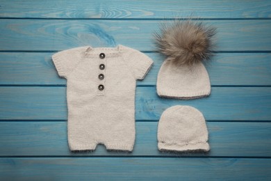 Photo of Set of cute baby knitwear for photoshoot on light blue wooden background, flat lay