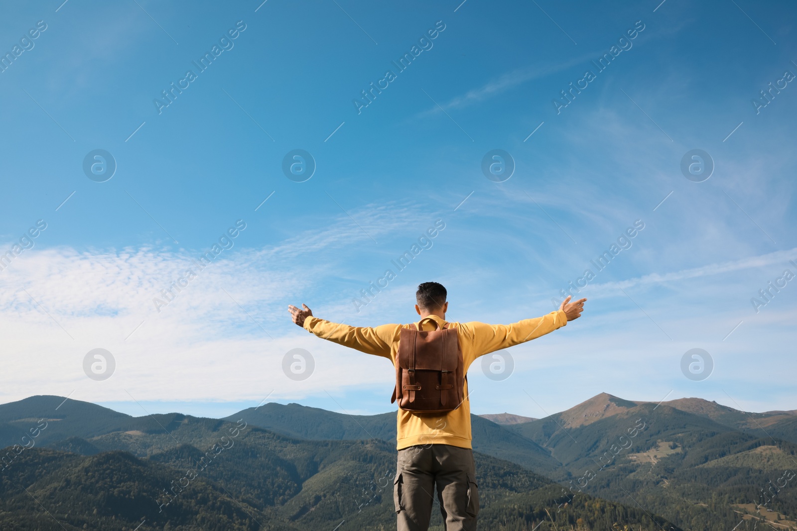 Photo of Tourist in mountains on sunny day, back view