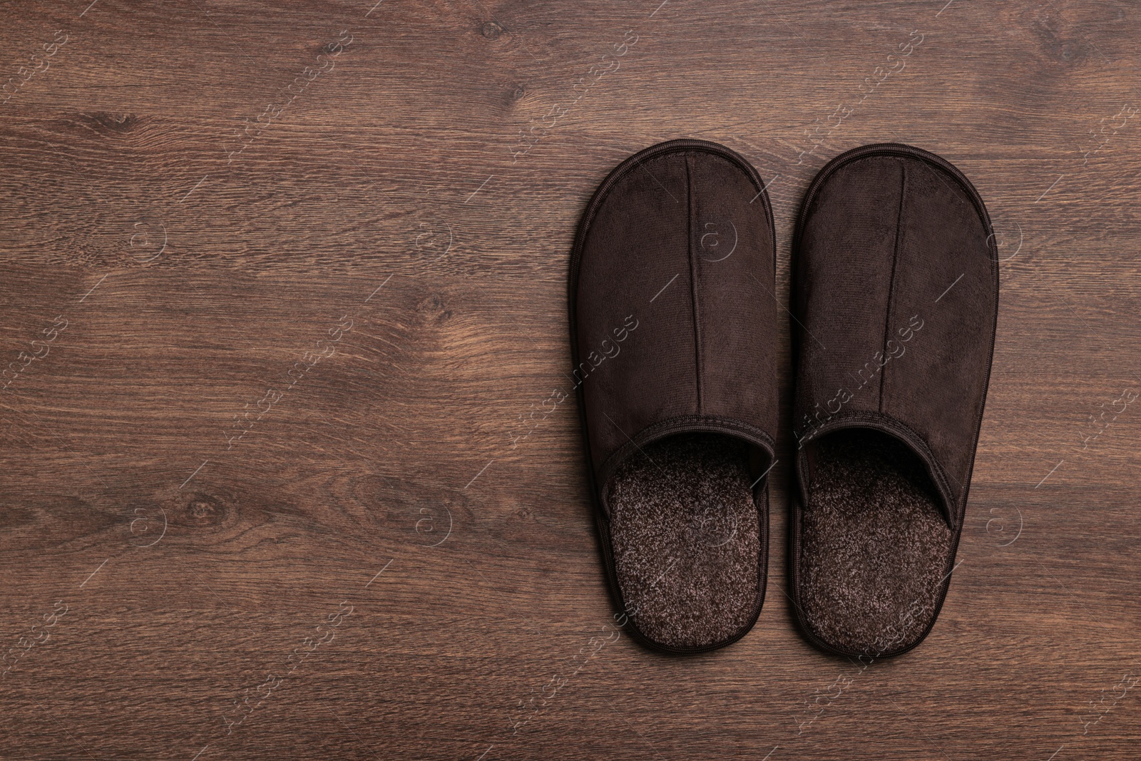 Photo of Pair of brown slippers on wooden floor, top view. Space for text