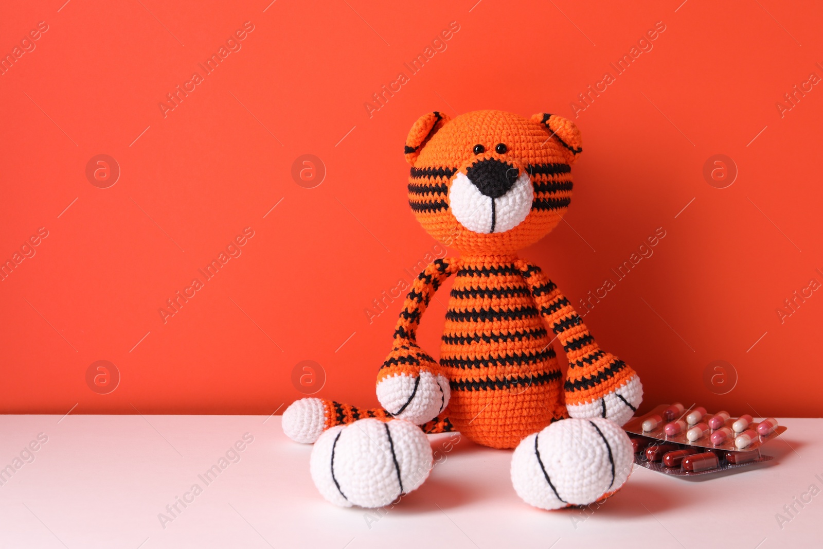 Photo of Toy tiger and pills on color background, space for text