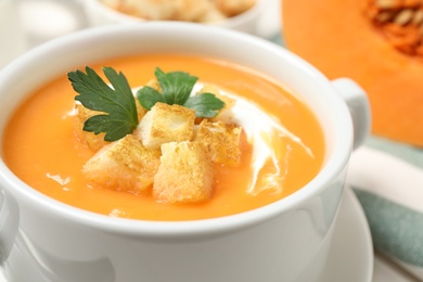 Photo of Delicious pumpkin soup in bowl on table, closeup