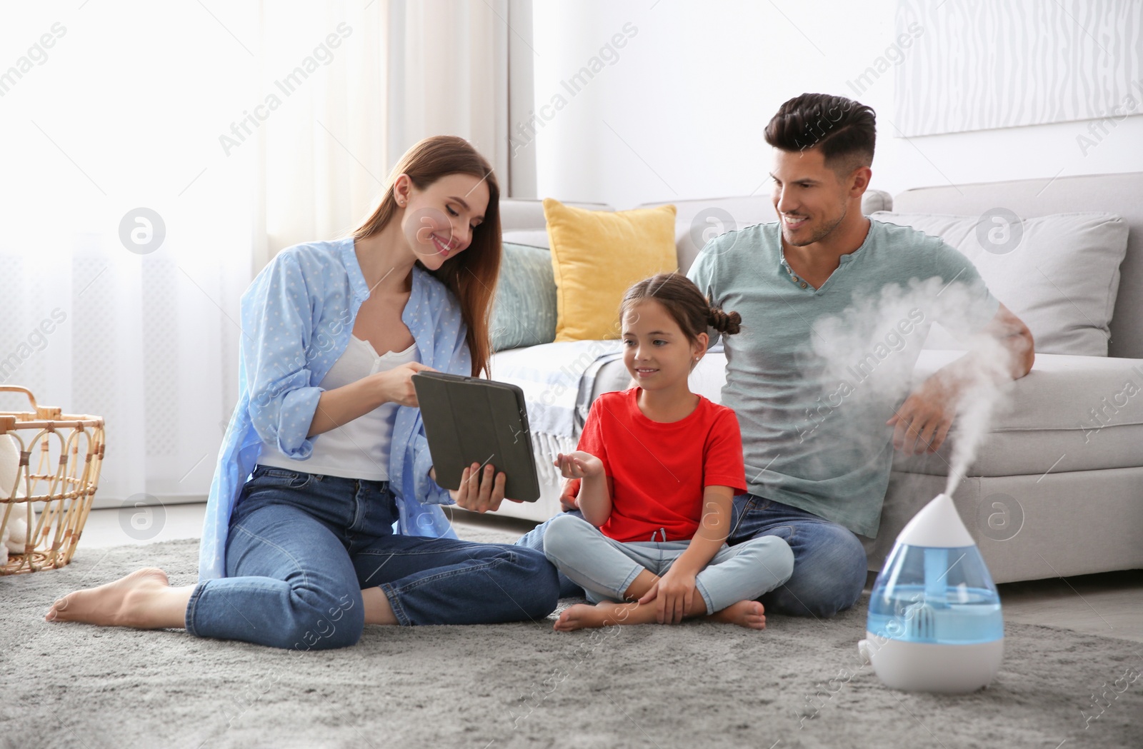 Photo of Family with tablet near modern air humidifier at home