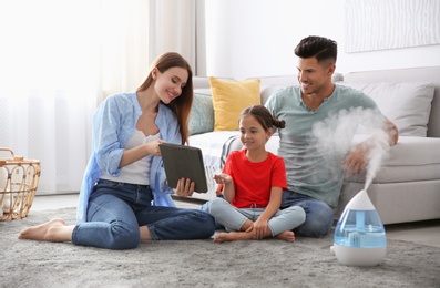 Photo of Family with tablet near modern air humidifier at home