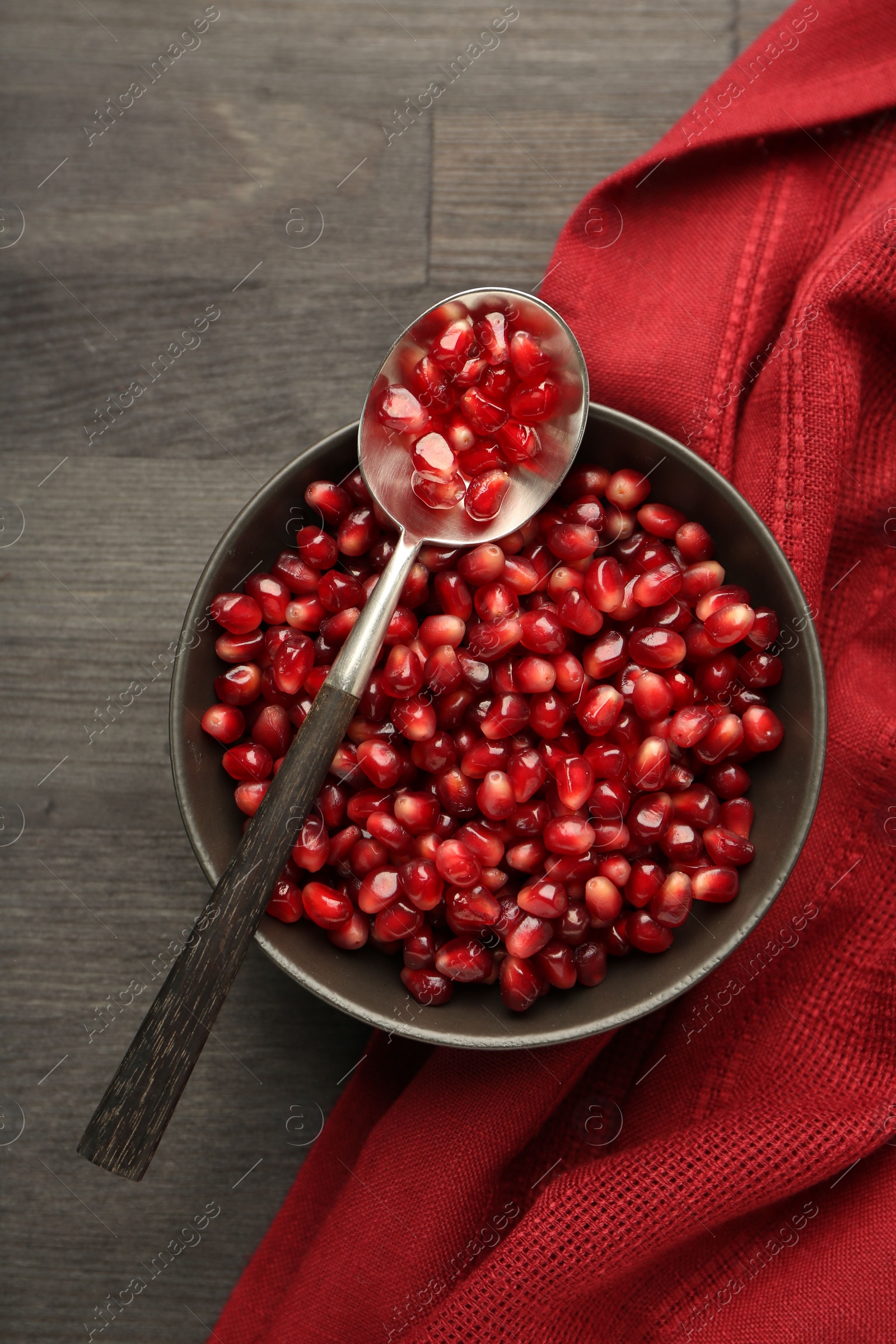 Photo of Tasty ripe pomegranate grains on dark wooden table, top view