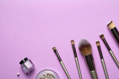 Flat lay composition with makeup brushes on lilac background. Space for text
