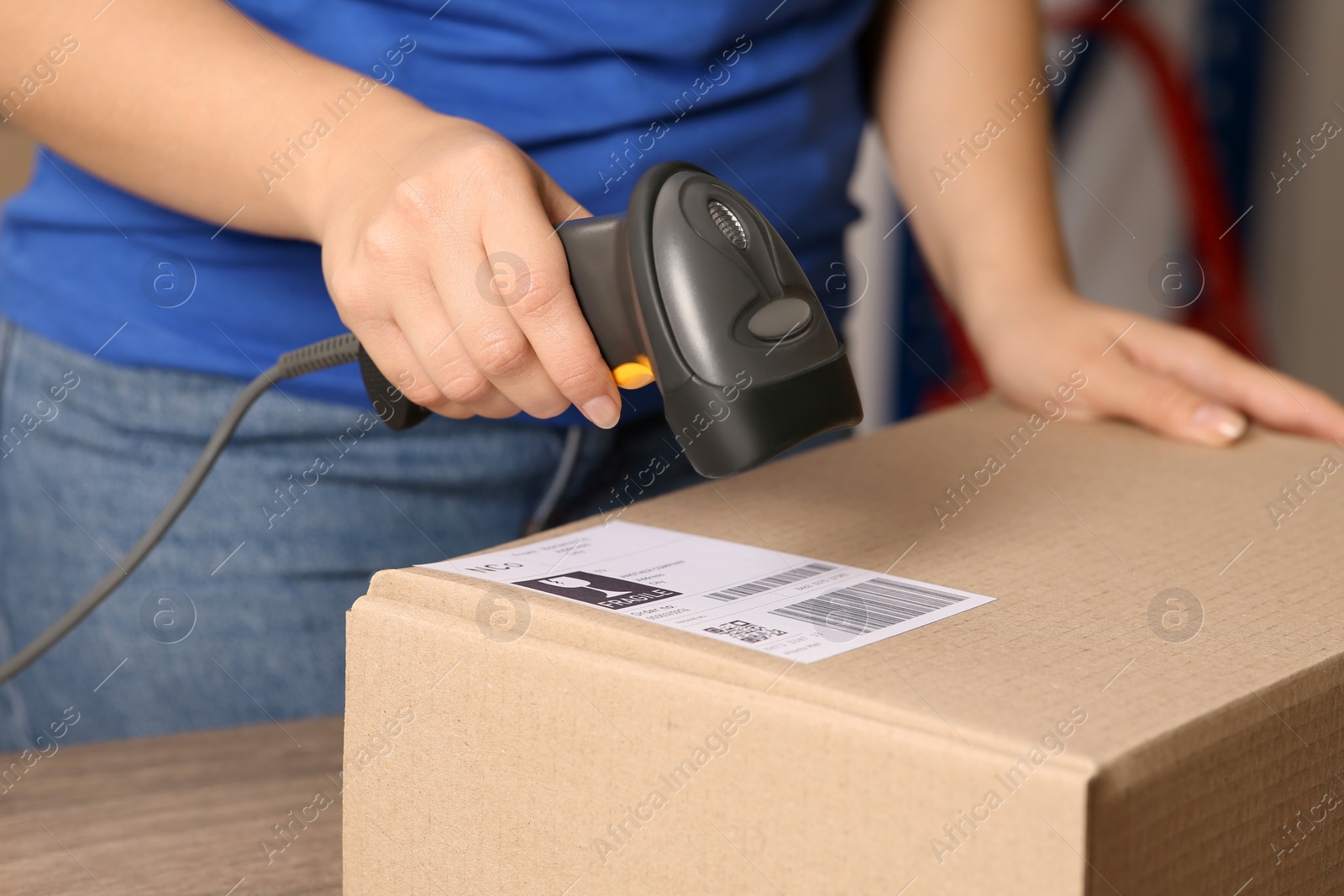 Photo of Post office worker with scanner reading parcel barcode at counter, closeup