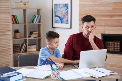 Photo of Dad helping his son with difficult homework assignment in room, space for text