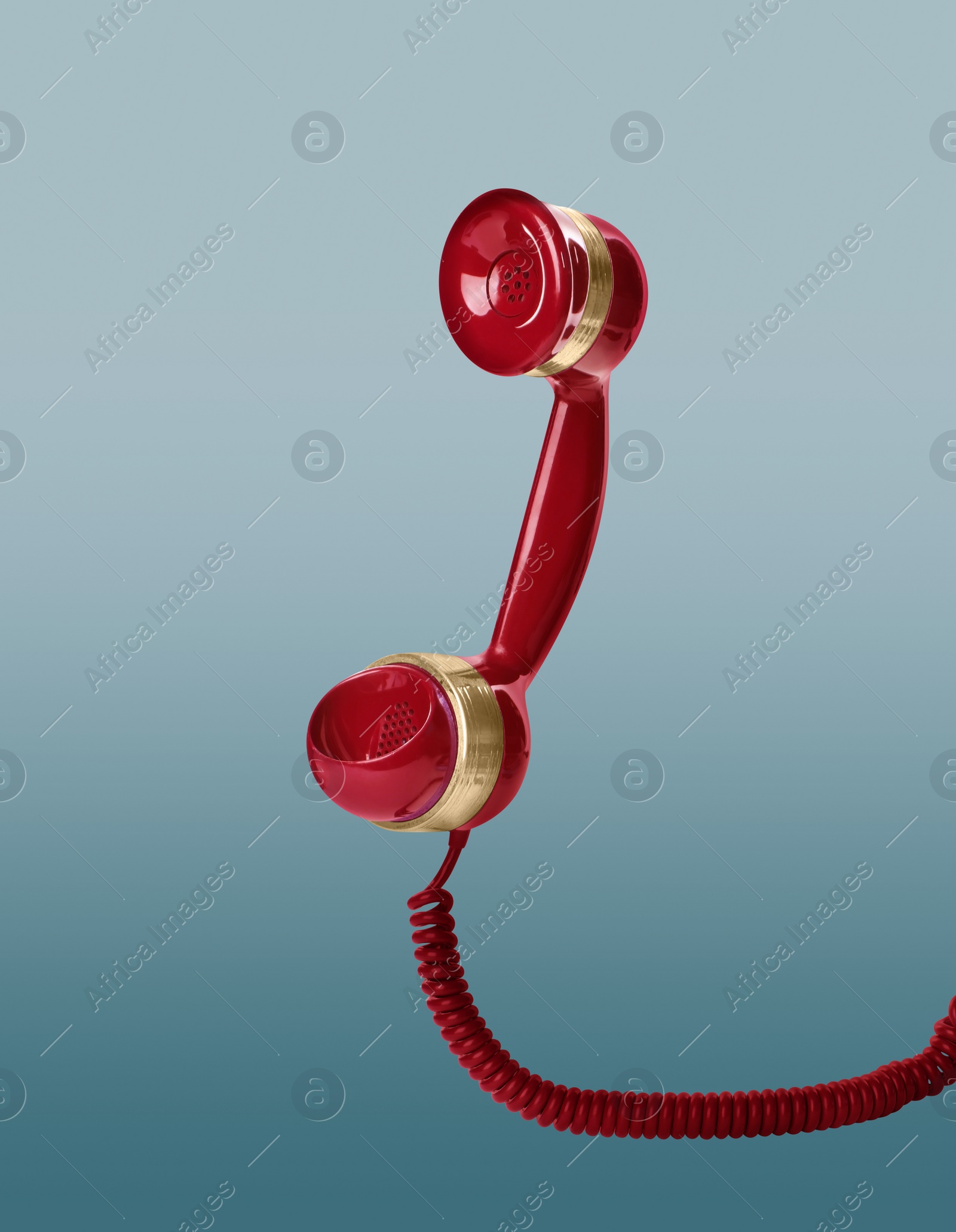 Image of Handset of vintage red corded telephone flying in air on light blue background