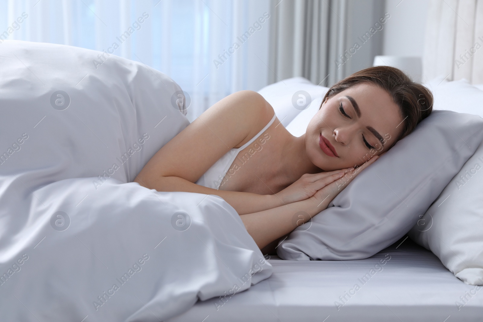 Photo of Young woman sleeping in comfortable bed with silky linens