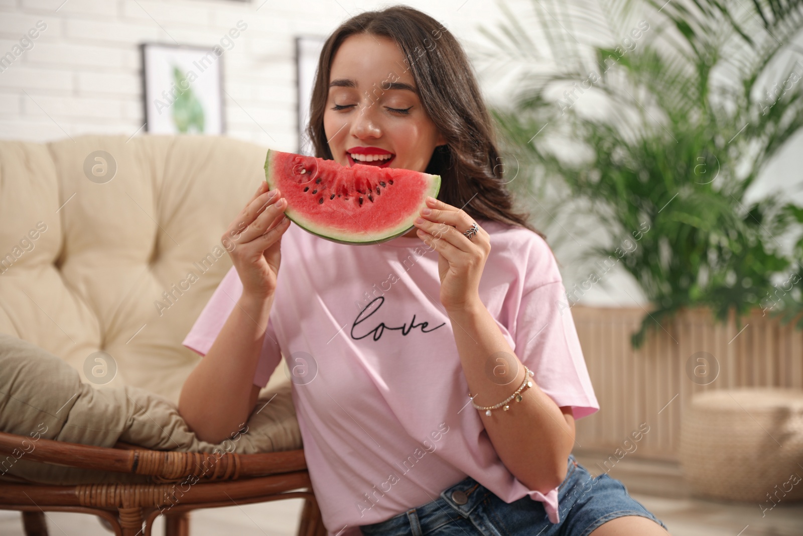 Photo of Beautiful young woman with watermelon at home