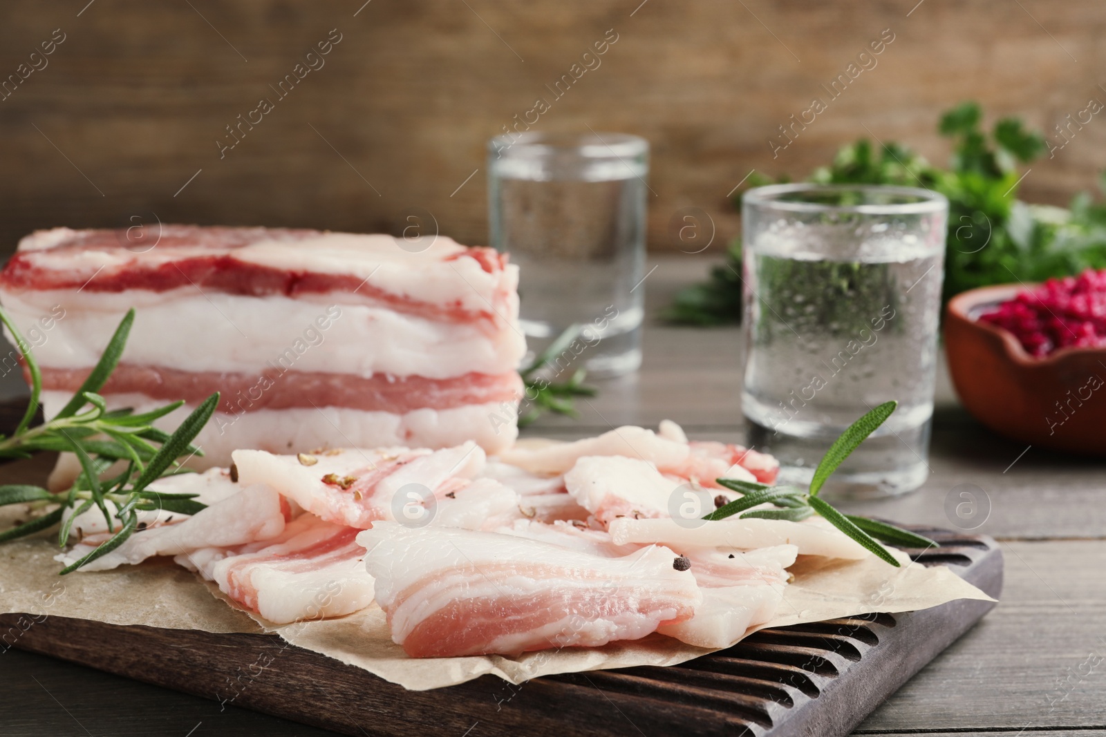 Photo of Tasty salt pork with rosemary on wooden board, closeup