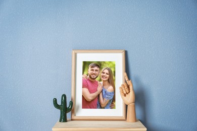 Portrait of happy young couple in photo frame on table near light blue wall