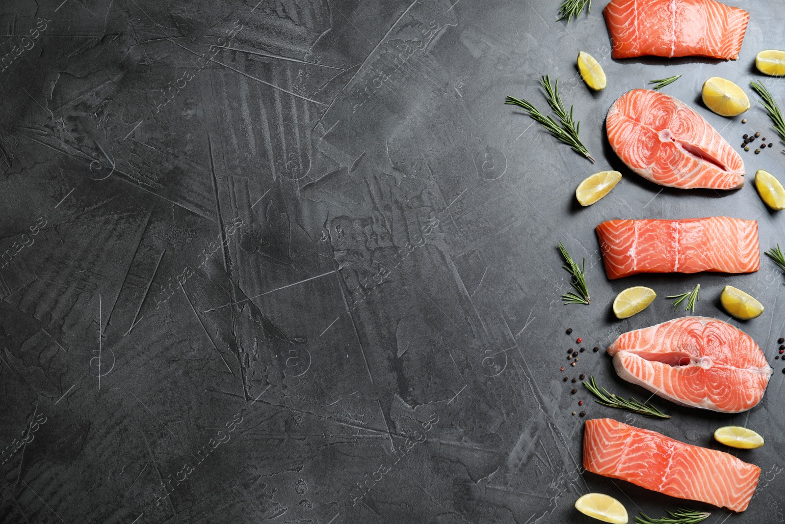 Photo of Flat lay composition with fresh raw salmon, rosemary and lemon on dark grey table, space for text. Fish delicacy