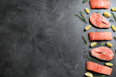 Photo of Flat lay composition with fresh raw salmon, rosemary and lemon on dark grey table, space for text. Fish delicacy