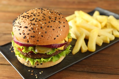Photo of Burger with delicious patty and french fries on wooden table, closeup