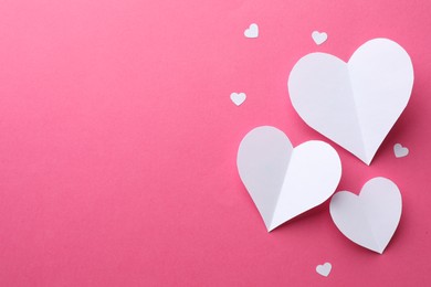 Photo of White paper hearts on pink background, flat lay. Space for text