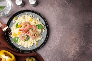 Photo of Tasty couscous with shrimps, bell pepper and basil on brown textured table, flat lay. Space for text